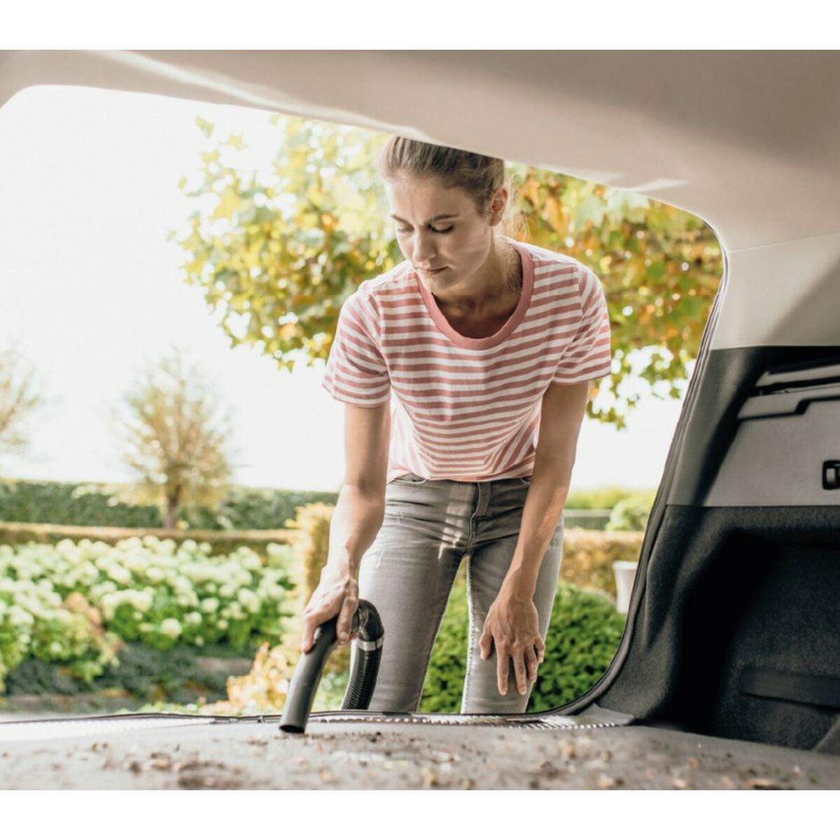Mujer limpiando el interior de un coche con aspiradora seco húmedo Kärcher 1000W.