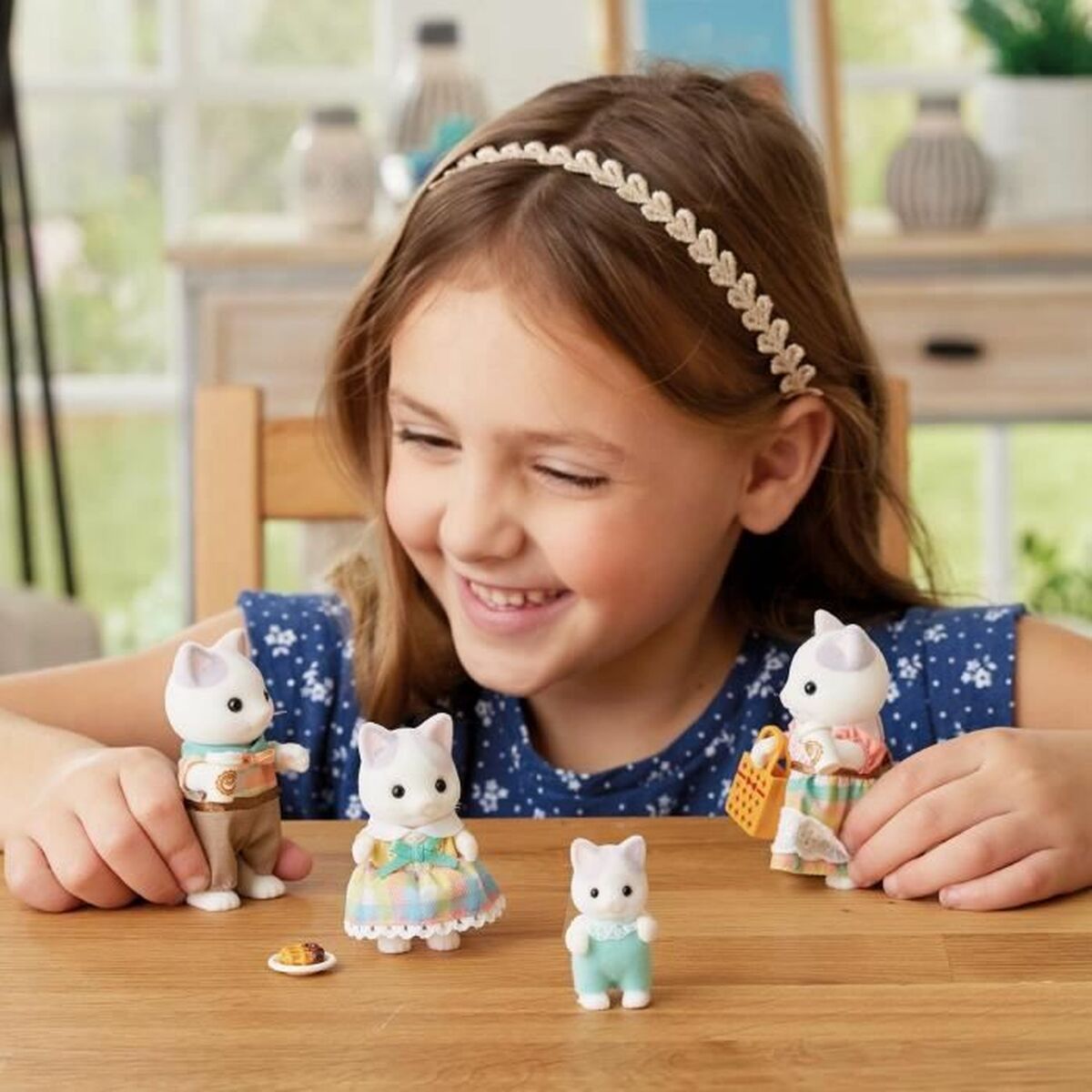 Niña jugando con los Accesorios para casa muñecas Sylvanian Families 5738 Latte Cat Family en mesa.
