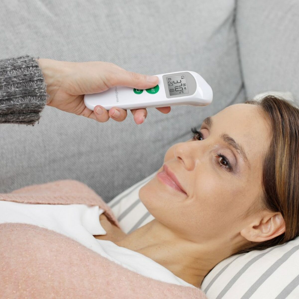 Mujer usando un Termómetro Medisana digital, control LCD en frente, para medir la temperatura de manera eficiente.
