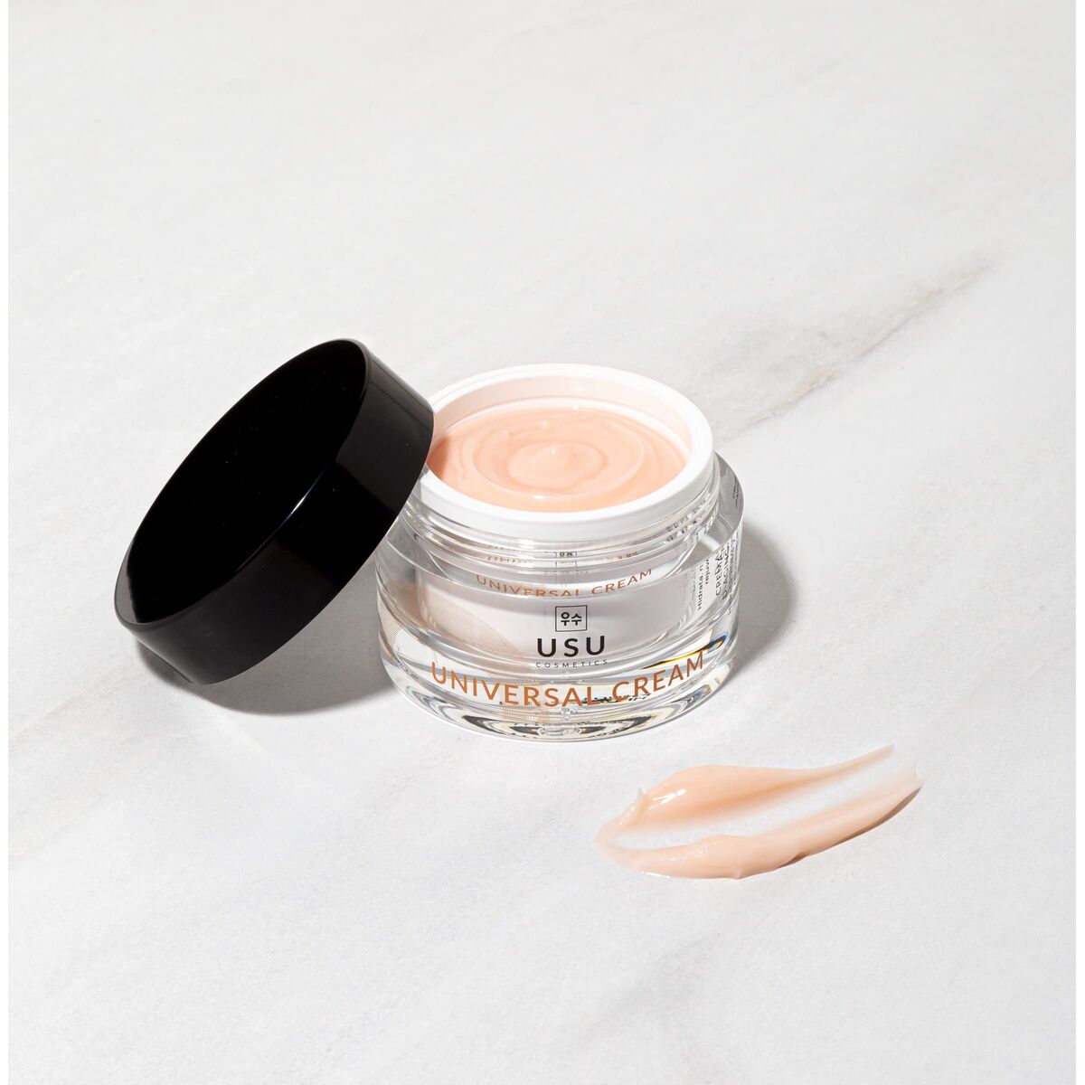 USU cosmetics universal facial cream in a jar with lid and a creamy texture on marble background.