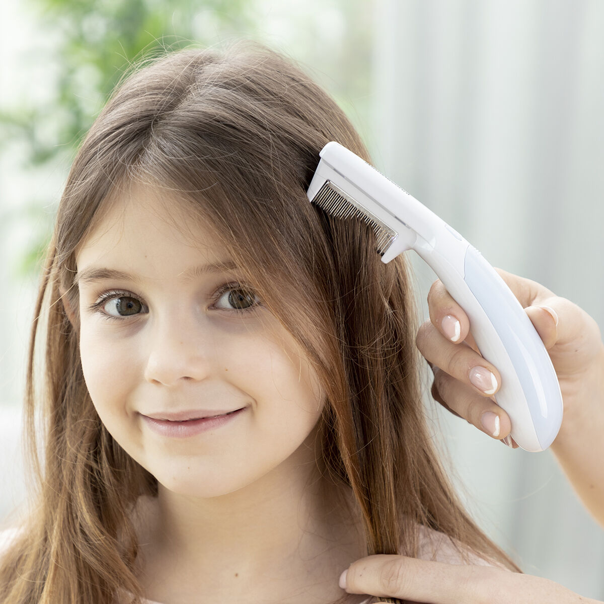 Girl using an electric lice comb with ergonomic handle for effective lice treatment.