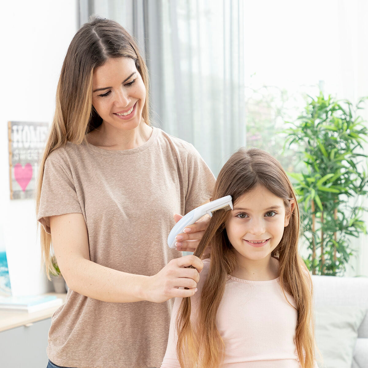 Mujer usando el peine eléctrico antipiojos con mango unlicer en el cabello de una niña, ideal para el cuidado personal. electric lice comb with ergonomic handle.